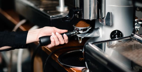 Barista sætter filterholderen med malet kaffe i en espressomaskine